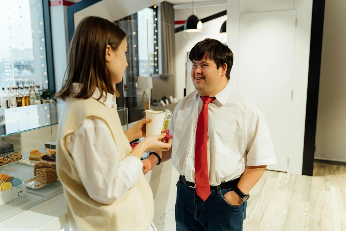 A male manager talks to a female client at his café.