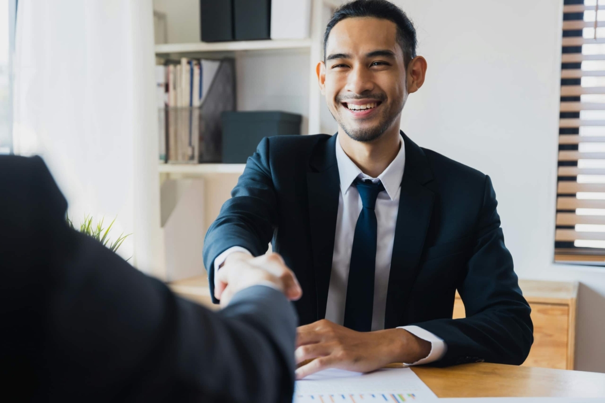 Businessman shaking hands with another person in an office.
