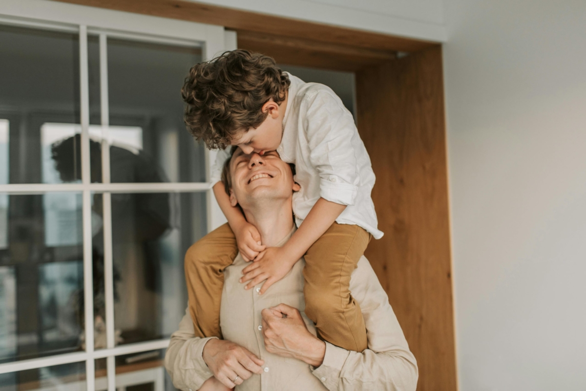 Father carrying his son on his shoulders in their home.