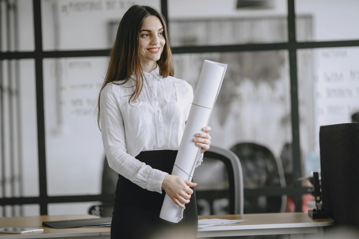 New manager holding large rolled up paper in an office.