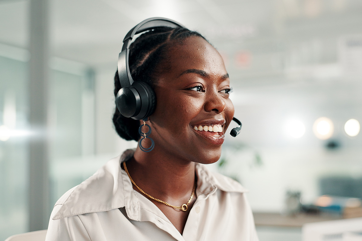 Closeup of smiling customer service employee talking on a headset.